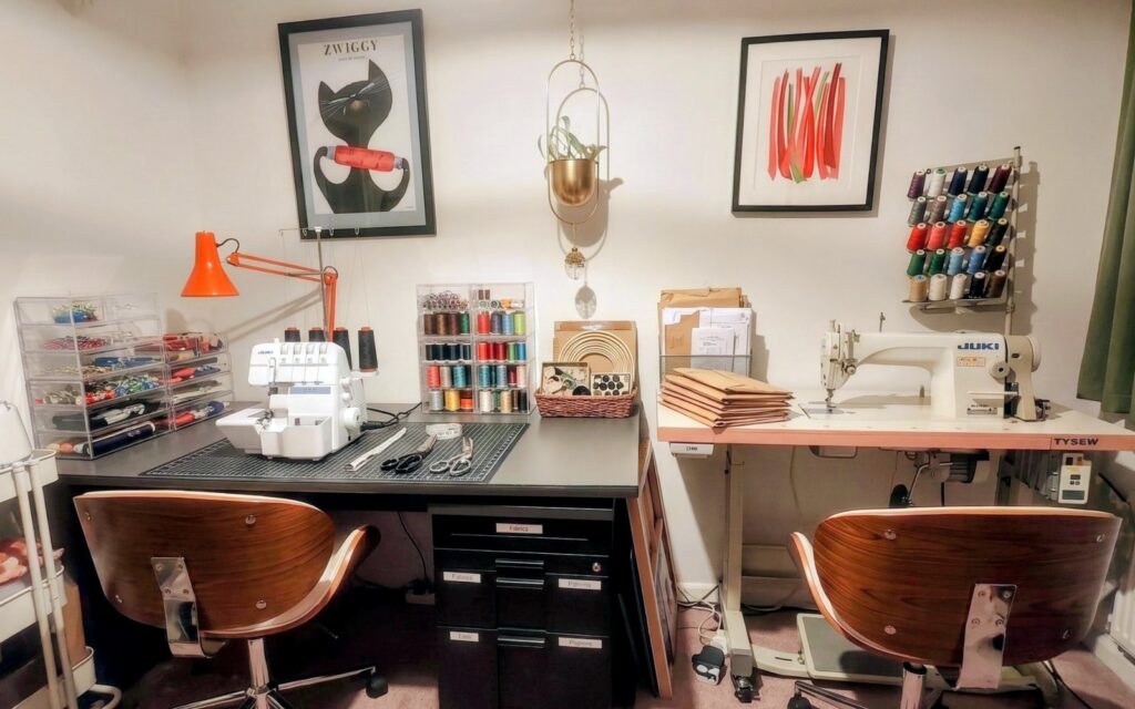 The studio: an industrial Juki on its stand, an overlocker, a wall of thread and a cutting table