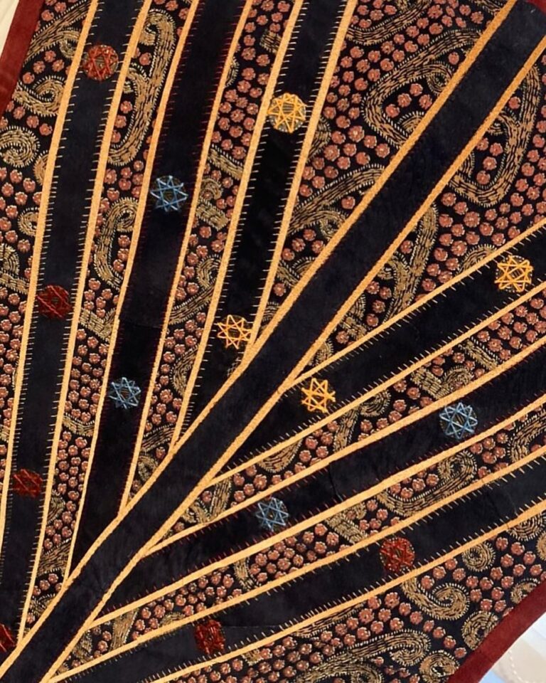 Radiating pleats edged in gold thread, fanning out from a single point