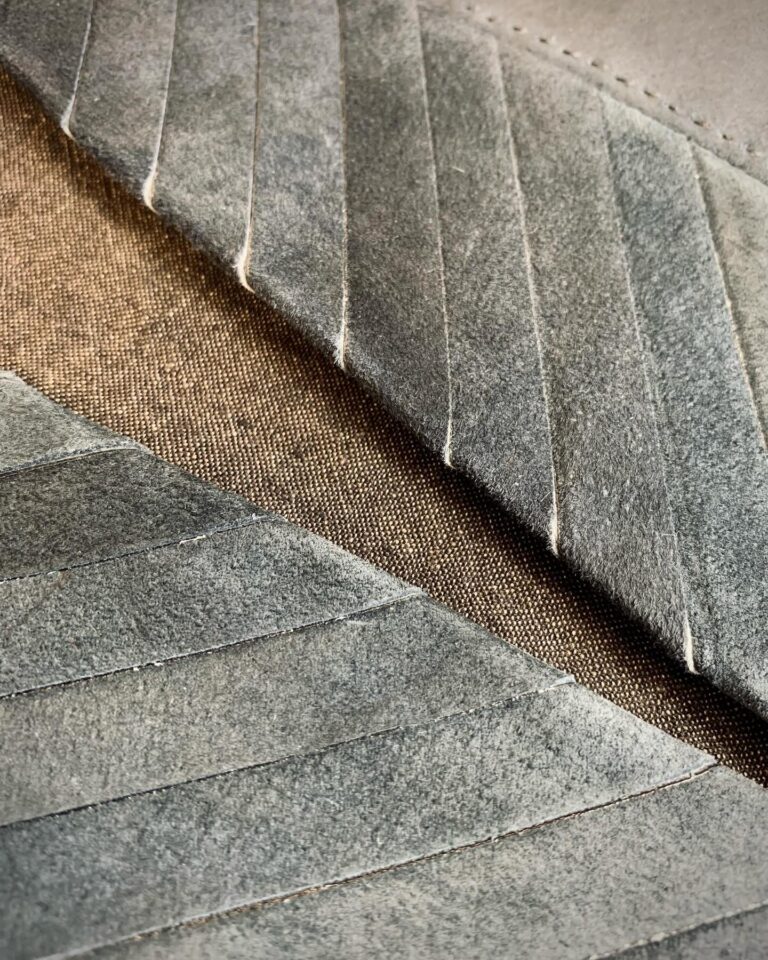 Angled suede panels pressed against an open-weave backing cloth, showing the seam allowances flattened by hand